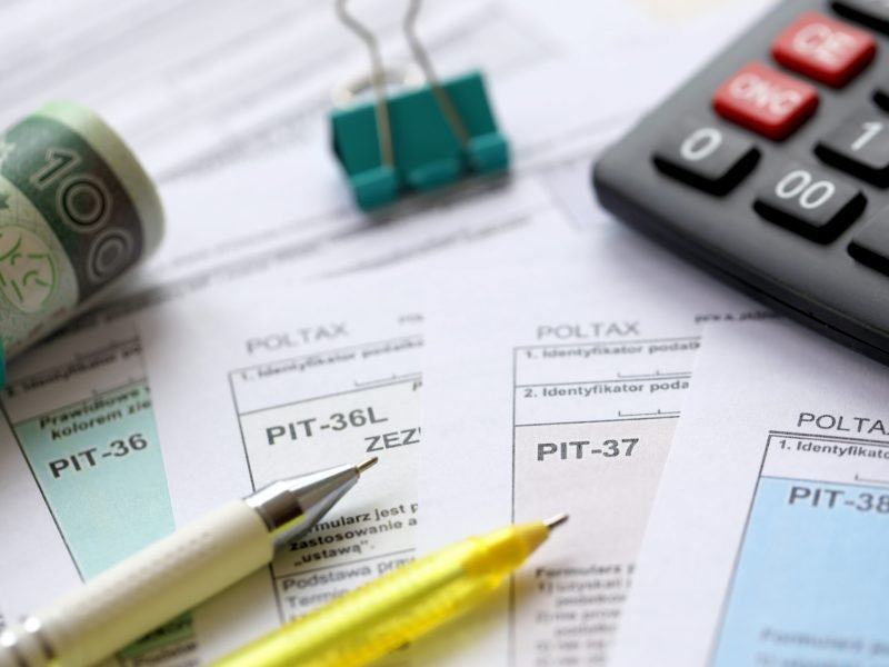 Declaration of the amount of earned income or incurred loss, PIT-36, PIT-36L, PIT-37 and PIT-38 tax forms on accountant table with pen and polish zloty money bills close up