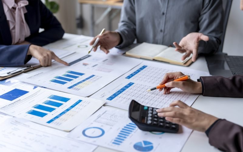 Business team analyzing financial data using calculator and spreadsheet for investment